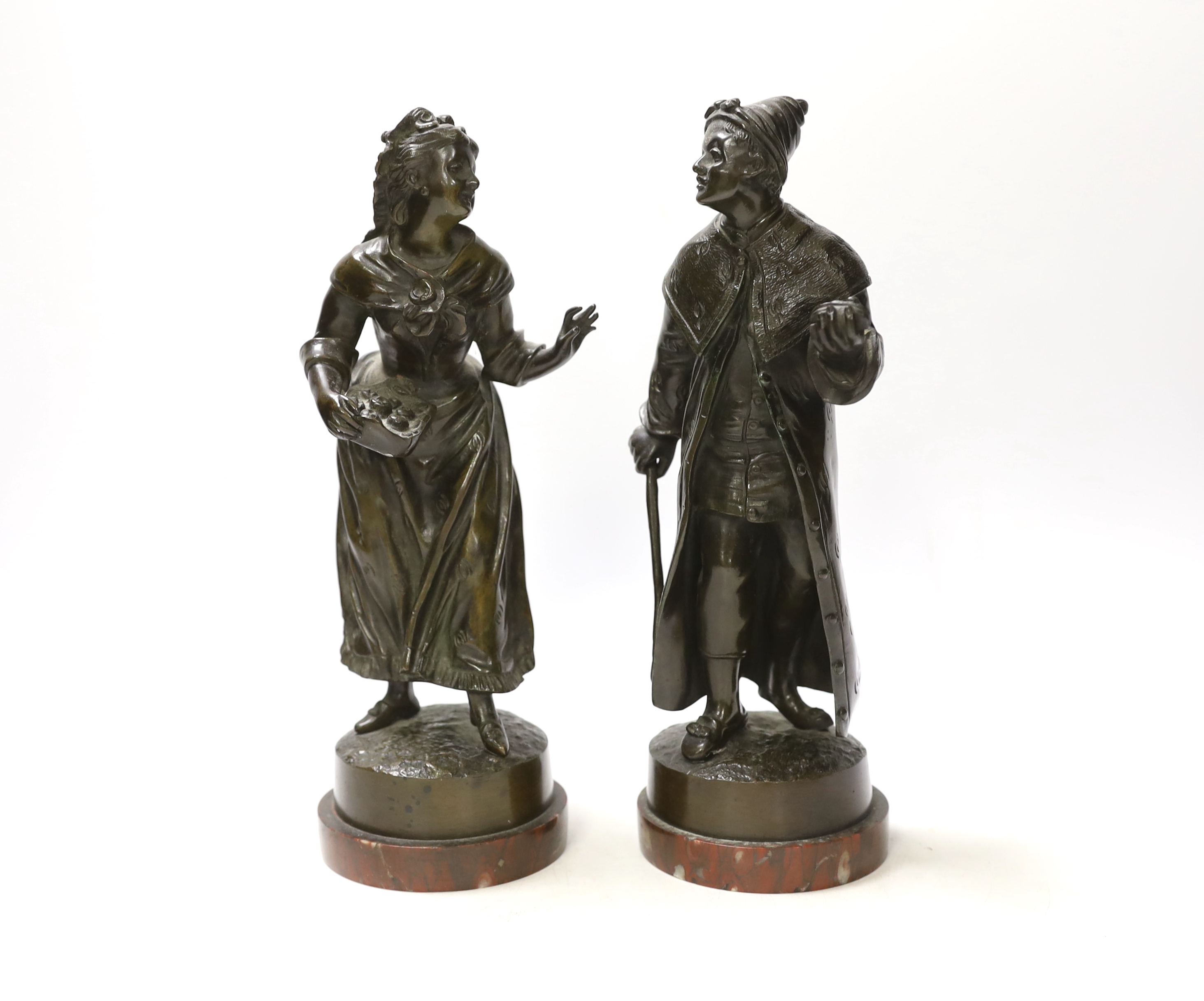 A pair of late 19th century French bronze figures of street sellers, Rouge marble bases, 25cm